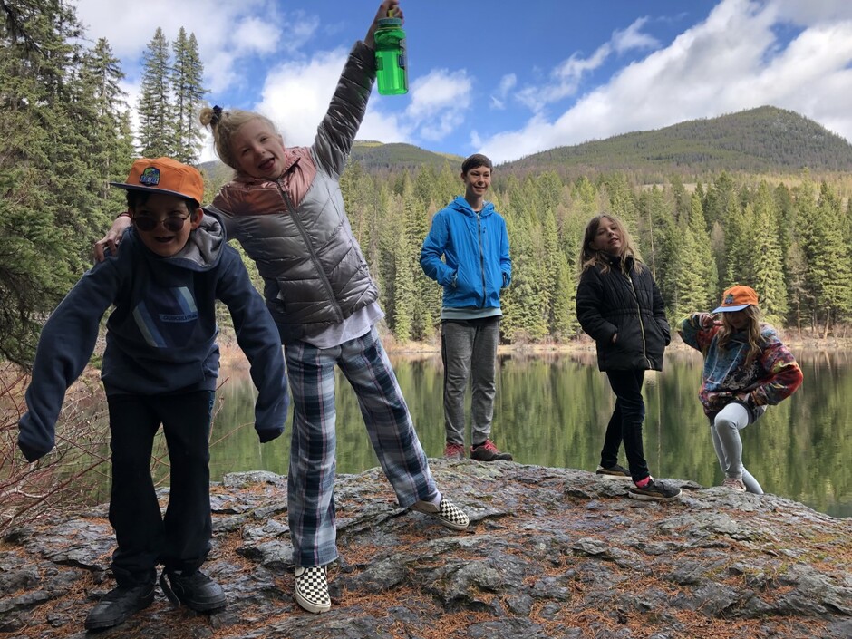 Five students on the bank of waterway with mountains in the background