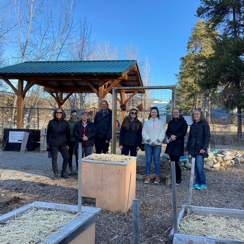 A group of eight people pose for a picture in a raised bed garden