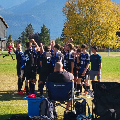 Group of teenage boys giving a cheers.  Coach in the front in chair