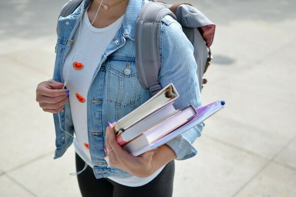 student holding books and wearing backpack