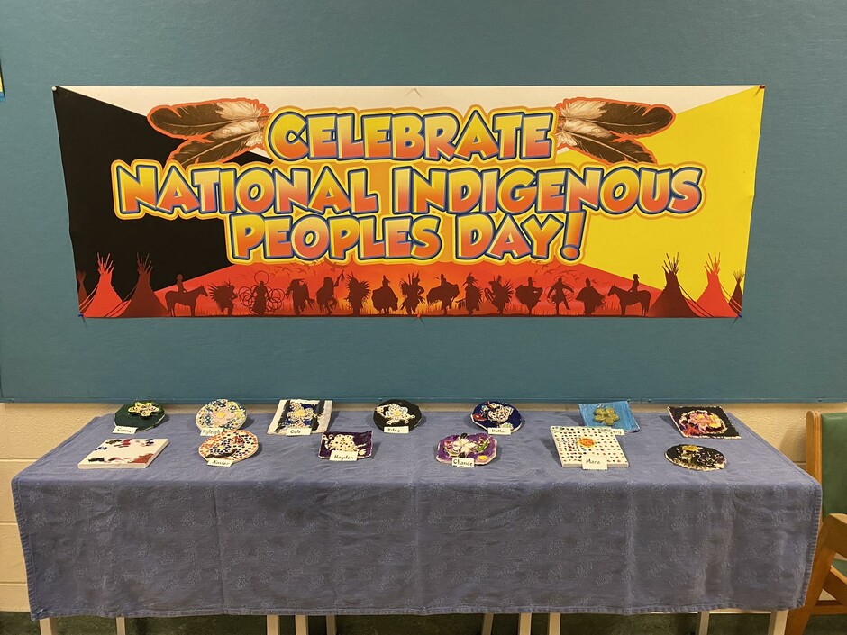 Sign that says "Celebrate National Indigenous Peoples Day!" with a table displaying art