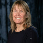 Middle aged woman with blonde shoulder length hair and wearing a black sweater