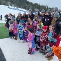 Students in traditional Indigenous regalia with Team Canada alpine athletes
